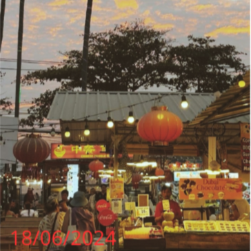 Evening street scene with palm trees, market stalls, and a colorful sky.